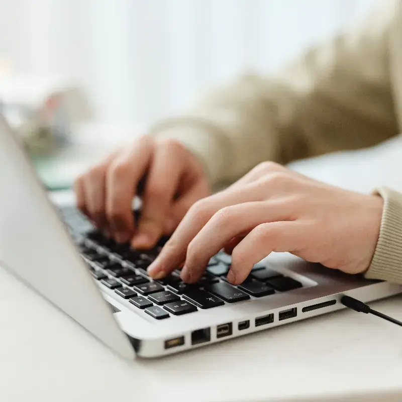 Hands typing on a laptop